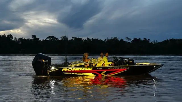 Navis 600X preto com detalhes em LED navegando ao entardecer no rio, com três pessoas a bordo